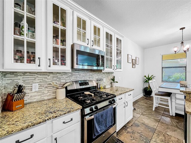 kitchen featuring a chandelier, decorative light fixtures, light stone countertops, appliances with stainless steel finishes, and white cabinets