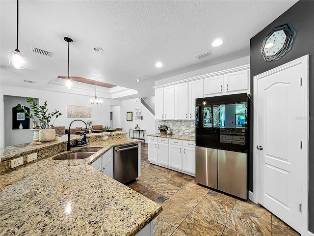 kitchen with white cabinets, decorative light fixtures, appliances with stainless steel finishes, sink, and a textured ceiling