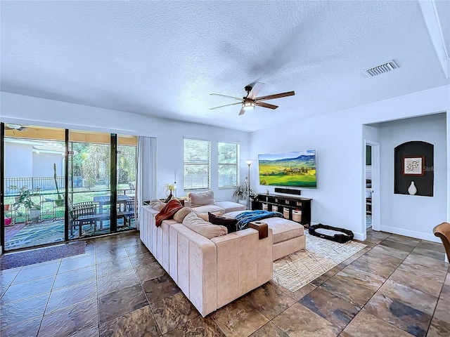 living room with a textured ceiling and ceiling fan