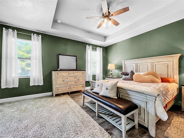 bedroom with multiple windows, ceiling fan, and dark hardwood / wood-style flooring