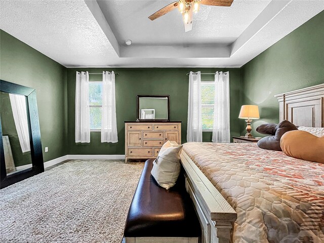 bedroom featuring a textured ceiling, ceiling fan, carpet floors, and multiple windows