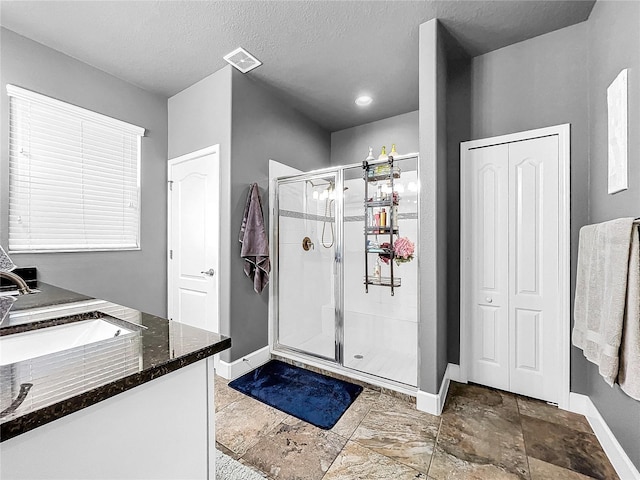 bathroom featuring a textured ceiling, vanity, and an enclosed shower