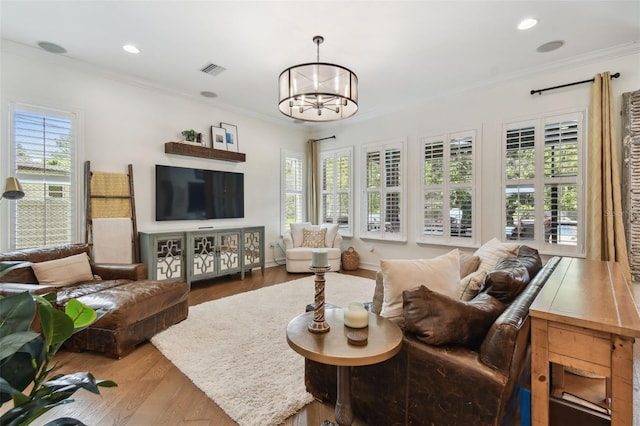 living room with light hardwood / wood-style flooring, crown molding, a chandelier, and a healthy amount of sunlight