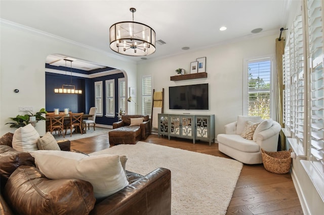 living room featuring crown molding, dark hardwood / wood-style flooring, and a chandelier