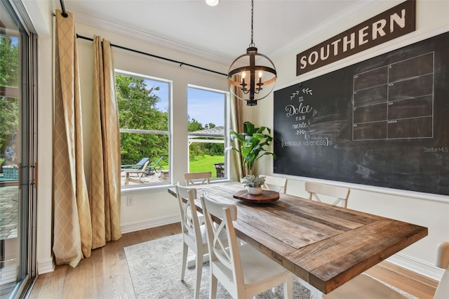 dining room with wood-type flooring, an inviting chandelier, crown molding, and a wealth of natural light