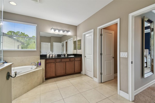 bathroom featuring vanity, a relaxing tiled tub, and tile patterned flooring