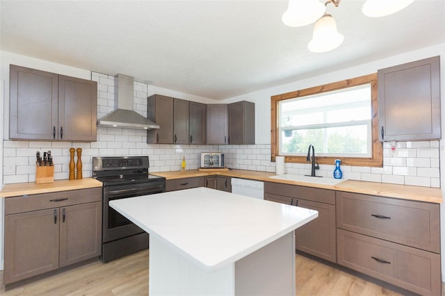 kitchen with light hardwood / wood-style floors, sink, wall chimney range hood, a kitchen island, and black range with electric cooktop