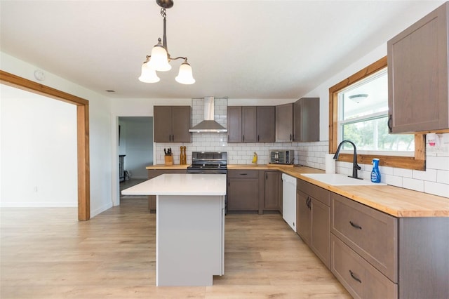 kitchen with stainless steel electric stove, wall chimney exhaust hood, dishwasher, a notable chandelier, and sink