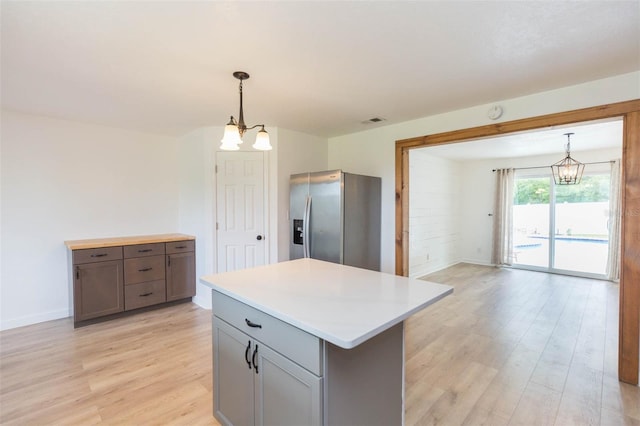 kitchen featuring stainless steel fridge, a center island, light hardwood / wood-style floors, and a chandelier