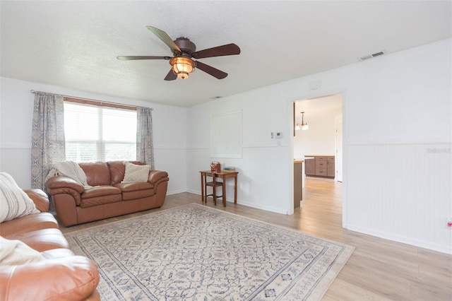 living room with ceiling fan with notable chandelier and light hardwood / wood-style floors