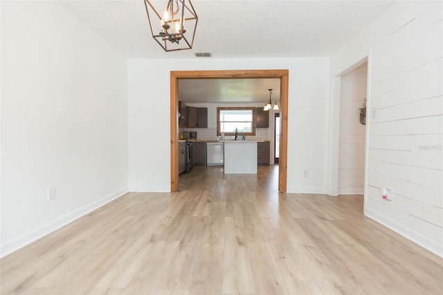 empty room featuring light hardwood / wood-style flooring, sink, and a notable chandelier