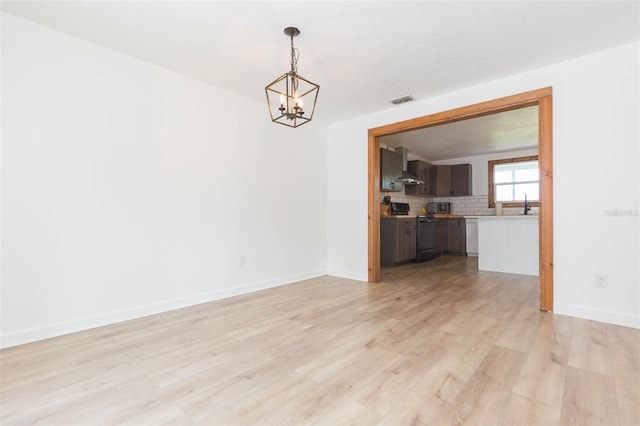 unfurnished room with a chandelier and light hardwood / wood-style flooring