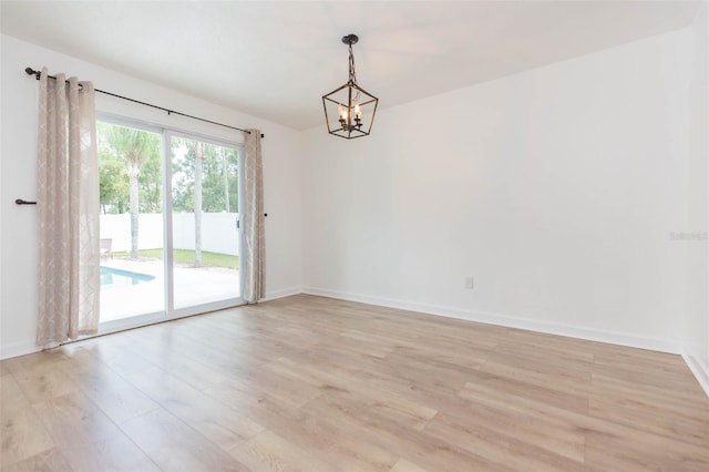 empty room featuring a notable chandelier and light hardwood / wood-style floors