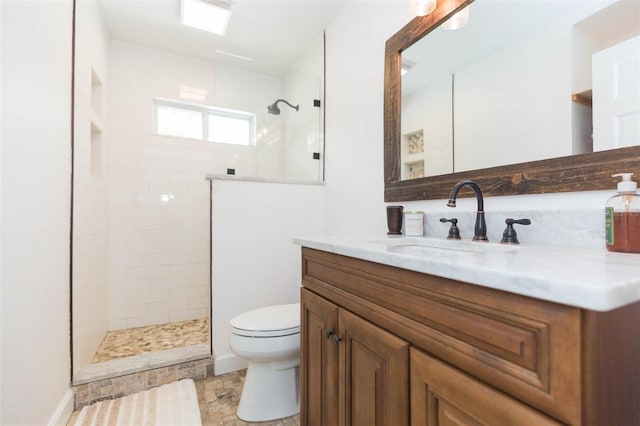 bathroom with vanity, toilet, and a tile shower