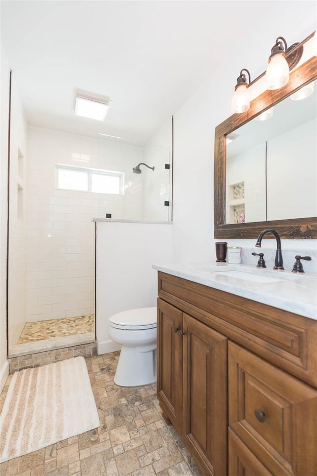 bathroom with vanity, toilet, and a tile shower