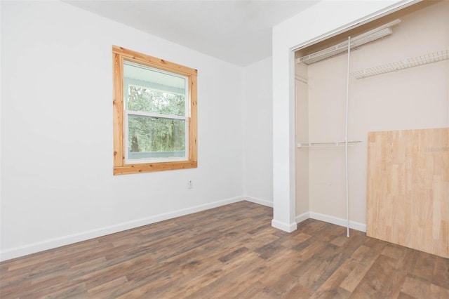 unfurnished bedroom with dark wood-type flooring and a closet