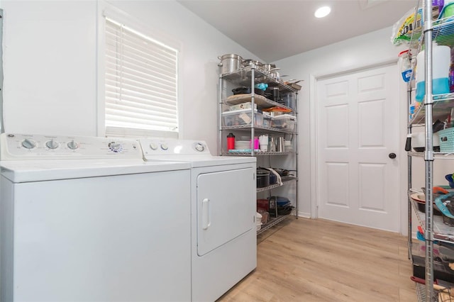 clothes washing area featuring washer and clothes dryer and light hardwood / wood-style flooring