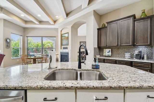 kitchen with light stone counters, sink, and dark brown cabinets