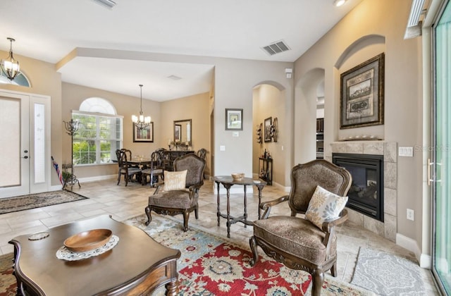 living area featuring a tiled fireplace, light tile patterned floors, and a notable chandelier