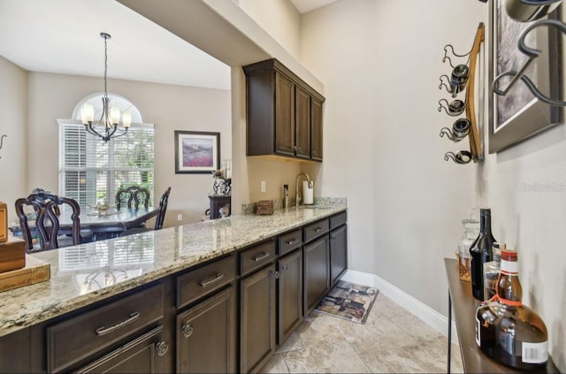 interior space with hanging light fixtures, light stone counters, an inviting chandelier, and dark brown cabinets