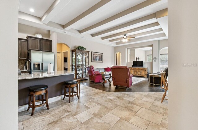 living room with ceiling fan, light hardwood / wood-style floors, beamed ceiling, and sink