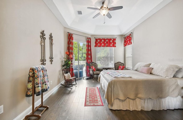 bedroom featuring a raised ceiling, ceiling fan, and dark hardwood / wood-style floors