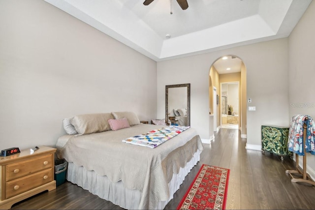 bedroom featuring dark wood-type flooring, a tray ceiling, and ceiling fan