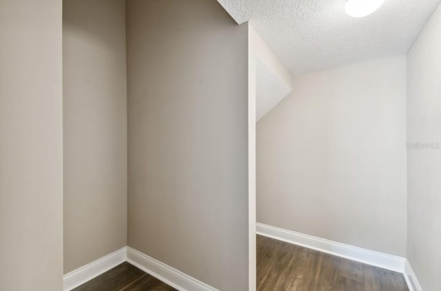 additional living space featuring a textured ceiling and dark hardwood / wood-style floors