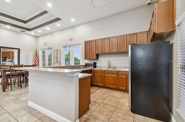 kitchen featuring french doors, sink, black refrigerator, kitchen peninsula, and light tile patterned flooring