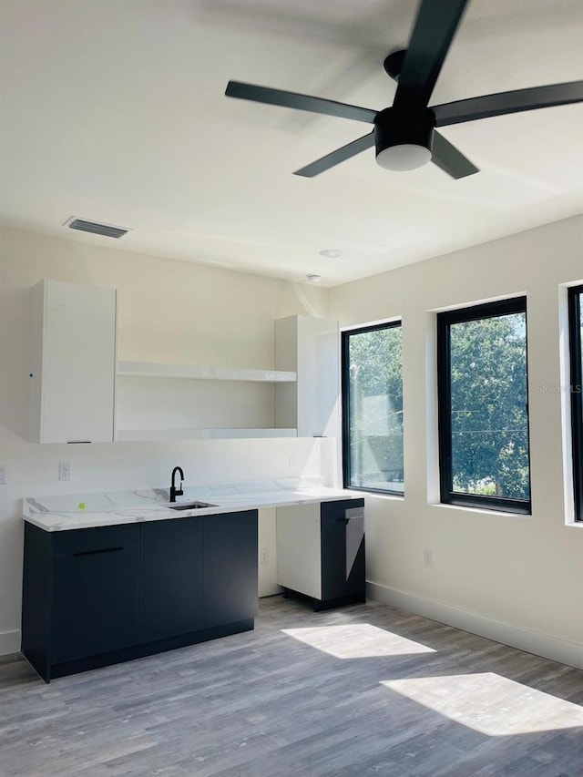 kitchen featuring white cabinetry, light hardwood / wood-style flooring, ceiling fan, and sink