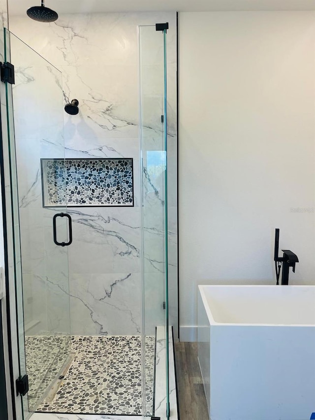 bathroom with wood-type flooring and independent shower and bath