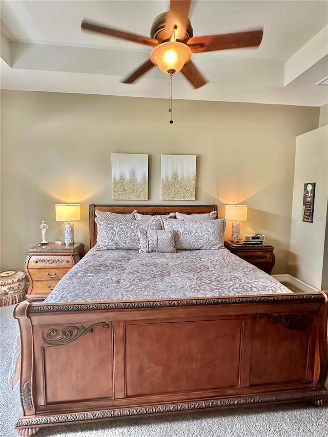 bedroom with ceiling fan, light colored carpet, and a raised ceiling