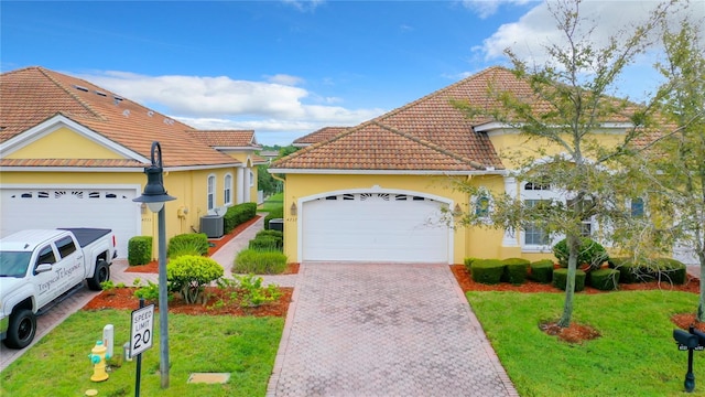 view of front of property with a front yard, a garage, and central AC unit