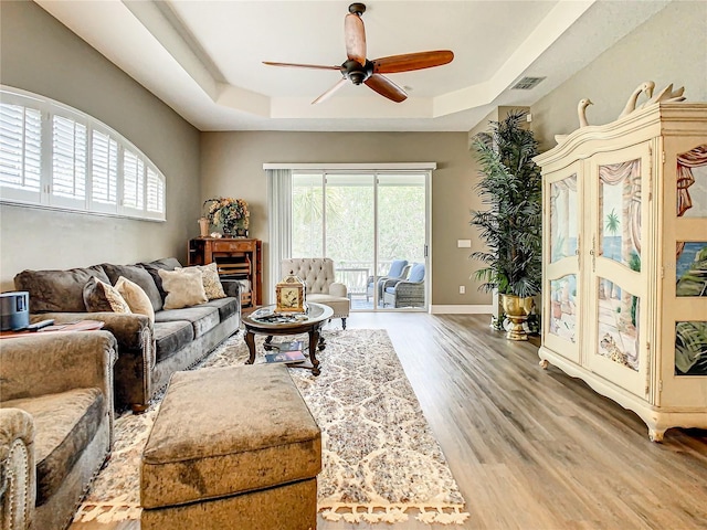 living room featuring ceiling fan, hardwood / wood-style flooring, and a raised ceiling