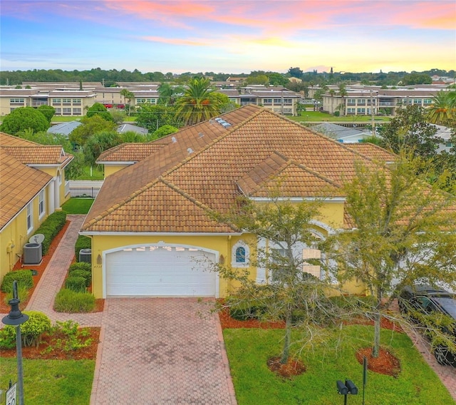 4737 Casswell Dr, New Port Richey, FL 34652 - view of front of home featuring central AC unit, a tile roof, an attached garage, stucco siding, and decorative driveway