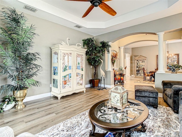4737 Casswell Dr, New Port Richey, FL 34652 - living room featuring ornate columns, arched walkways, a ceiling fan, wood finished floors, and a raised ceiling