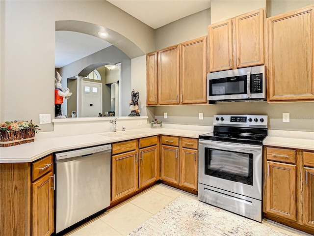4737 Casswell Dr, New Port Richey, FL 34652 - kitchen with appliances with stainless steel finishes, a sink, light countertops, arched walkways, and light tile patterned flooring