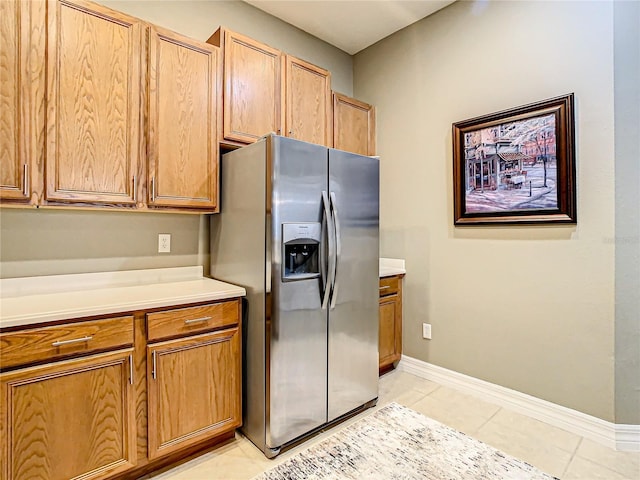 4737 Casswell Dr, New Port Richey, FL 34652 - kitchen featuring stainless steel fridge, light countertops, light tile patterned flooring, baseboards, and brown cabinetry