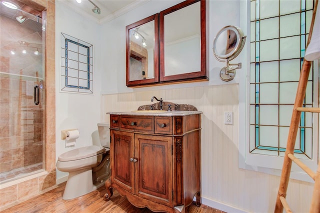 bathroom featuring toilet, ornamental molding, a stall shower, vanity, and wood finished floors