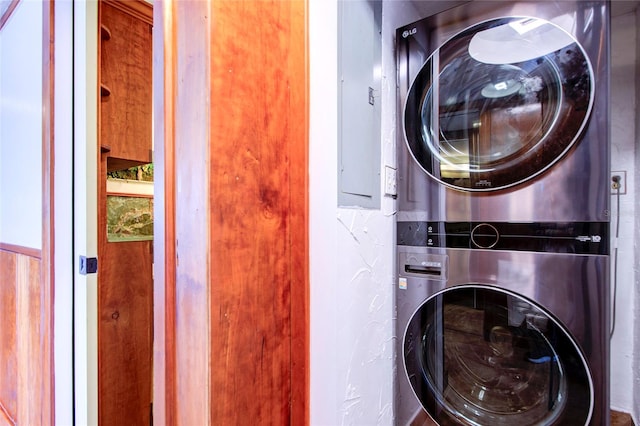 laundry room featuring laundry area, electric panel, and stacked washer / drying machine