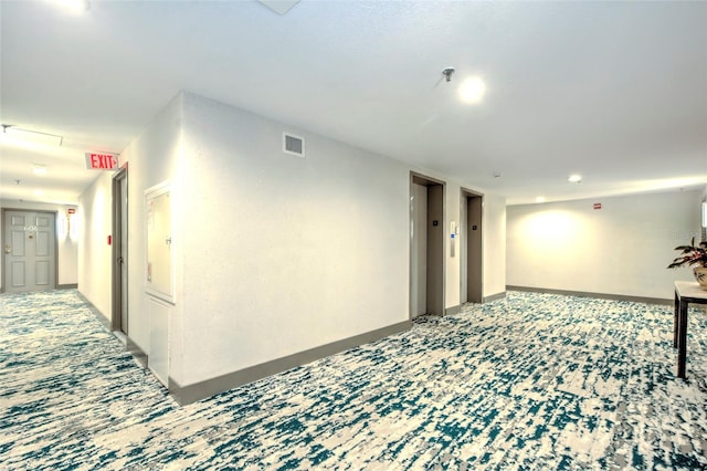 hallway with baseboards, carpet floors, visible vents, and elevator