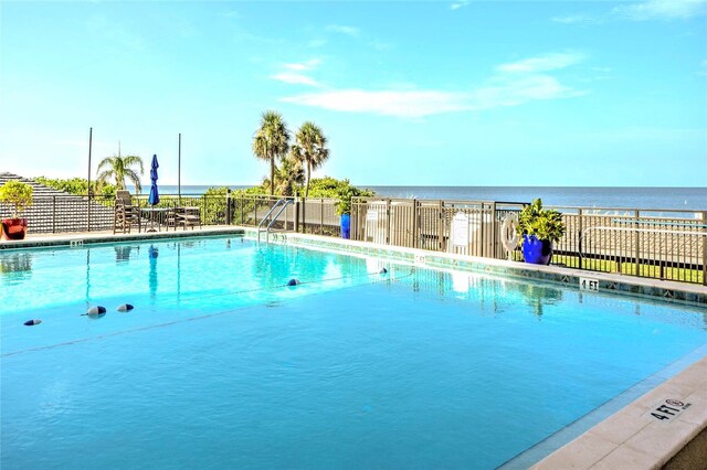 pool with a water view and fence