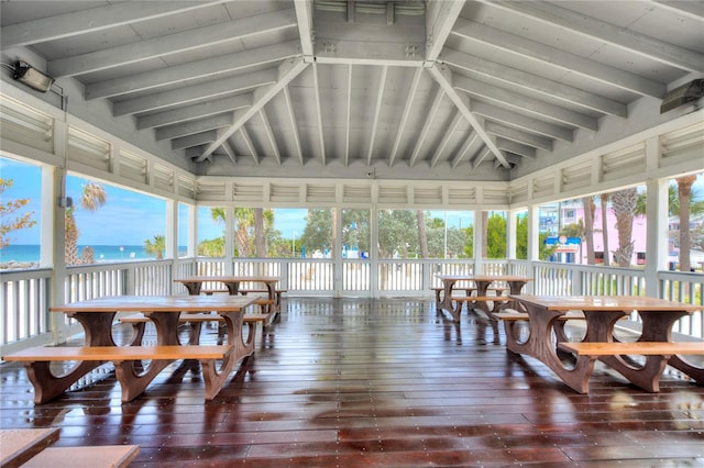 sunroom / solarium featuring a water view and lofted ceiling with beams