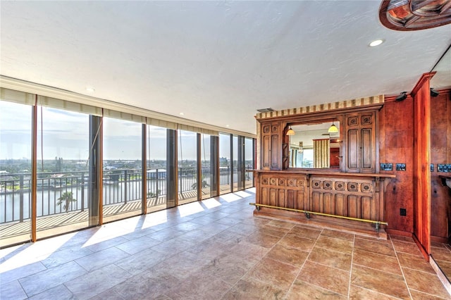 kitchen with recessed lighting, a water view, stone finish flooring, a textured ceiling, and a wall of windows