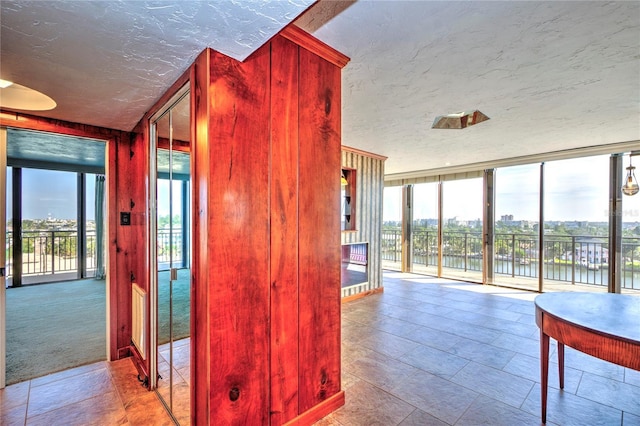 corridor featuring a water view, plenty of natural light, floor to ceiling windows, and a textured ceiling