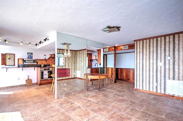 dining room with wooden walls, visible vents, a wainscoted wall, and a textured ceiling