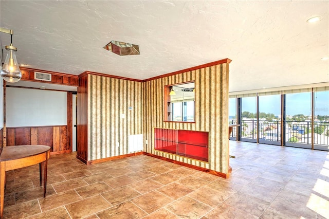 spare room featuring visible vents, wainscoting, radiator heating unit, a textured ceiling, and floor to ceiling windows