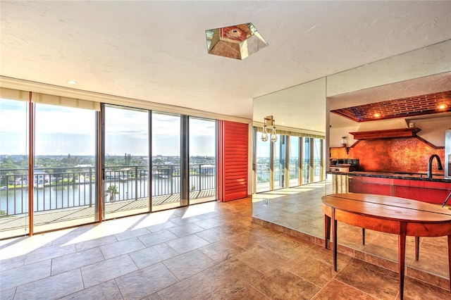 interior space featuring expansive windows, tasteful backsplash, a water view, and a sink