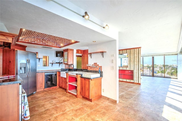 kitchen featuring stainless steel refrigerator with ice dispenser, dishwasher, open shelves, a wall of windows, and dark countertops