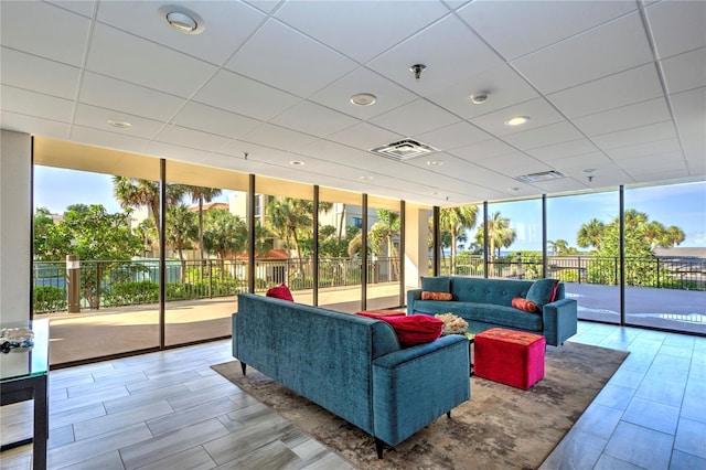 living room with visible vents, floor to ceiling windows, and a drop ceiling